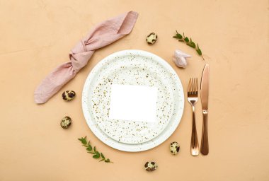 Stylish table setting with blank card and Easter eggs on color background