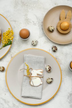 Table setting with Easter eggs and mimosa flowers on white grunge background