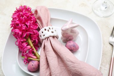 Table setting with Easter eggs, hyacinth flowers and bunny on white grunge background