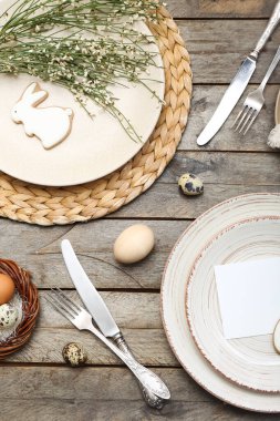 Table setting with Easter eggs, bunny and cutlery on wooden background