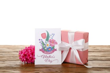 Greeting card with text HAPPY MOTHER'S DAY, hyacinth flower and gift on table against white background