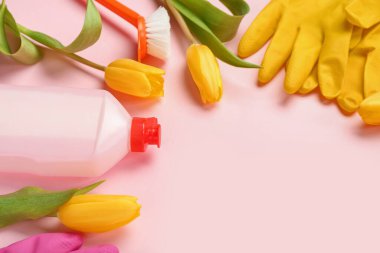 Frame made of cleaning supplies and tulips on pink background, closeup. Hello spring