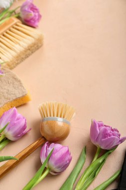 Cleaning brushes with sponge and tulips on beige background, closeup. Hello spring