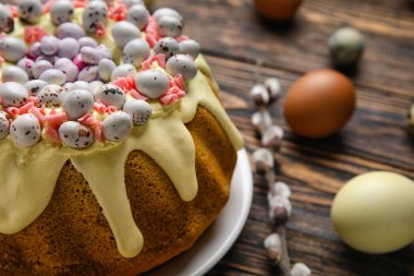 Tasty Easter cake and eggs on wooden table, closeup