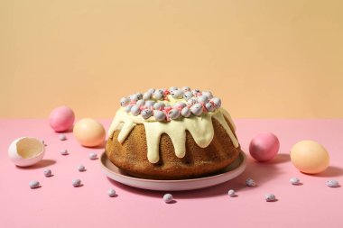 Composition with tasty Easter cake, eggs and candies on color background