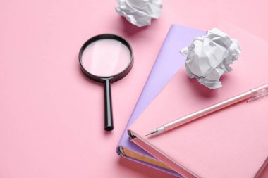 Books, pen, magnifier and crumpled paper on pink background, closeup. World Poetry Day celebration