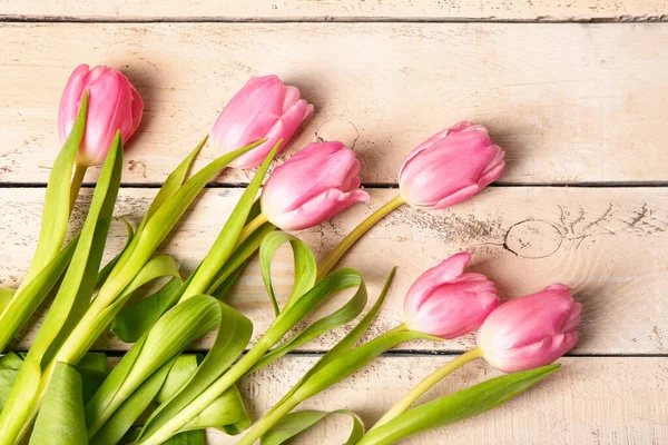 Beautiful tulip flowers on beige wooden background