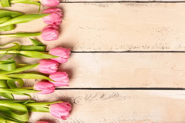Beautiful tulip flowers on beige wooden background