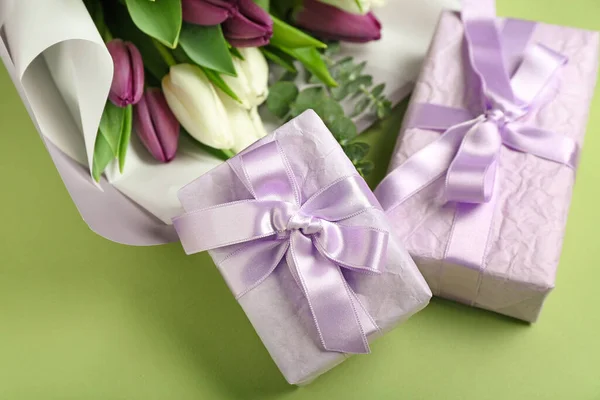 Gift boxes and bouquet of beautiful tulip flowers on green background. Hello spring