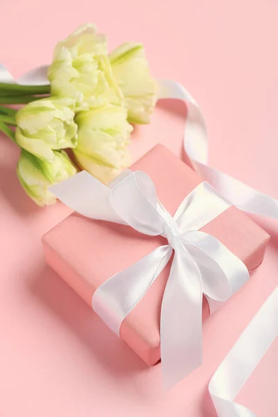 Gift box, ribbon and beautiful tulip flowers on pink background. Hello spring