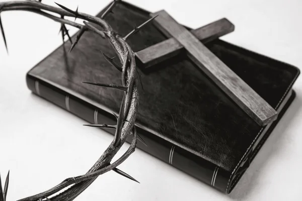 Holy Bible with cross and crown of thorns on white background, closeup