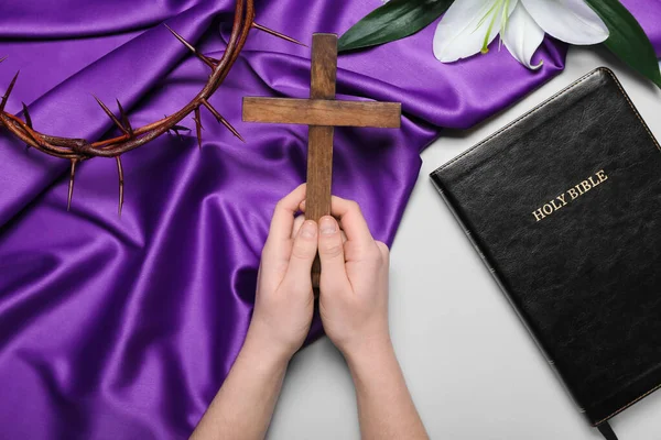 Woman praying with wooden cross on light background. Good Friday concept