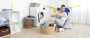 Stressed man doing laundry in bathroom