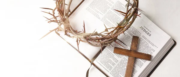 Crown of thorns with Holy Bible and cross on white background, top view