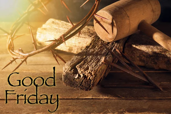 Crown of thorns with cross, mallet, nails and text GOOD FRIDAY on wooden background