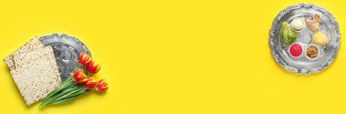 Banner with Passover Seder plates, flatbread matza and flowers on yellow background