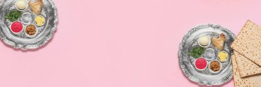 Banner with Passover Seder plates and flatbread matza on pink background