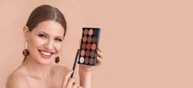 Young woman with beautiful eyeshadows on beige background with space for text