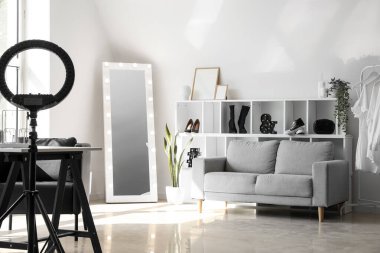 Interior of light makeup room with mirror, shelving unit and sofa