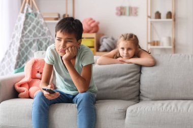 Tired little boy and girl watching cartoons on TV at home