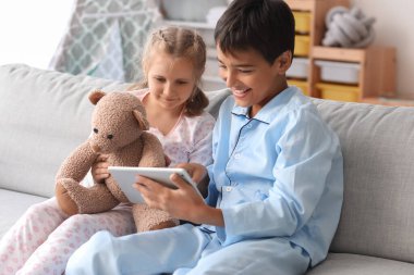 Little boy with his sister watching cartoons on tablet computer at home