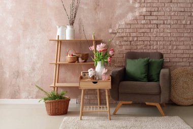 Vase with tulips, Easter bunny and cake on end table in living room near brick wall