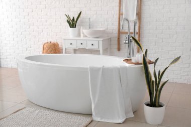 Interior of light bathroom with bathtub, sink and ladder