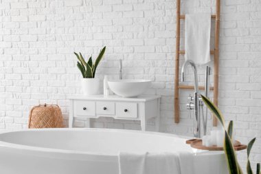 Interior of light bathroom with bathtub, sink and ladder