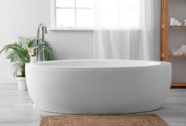 White bathtub in interior of light bathroom