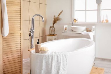 Interior of bathroom with modern bathtub and ceramic sink near window