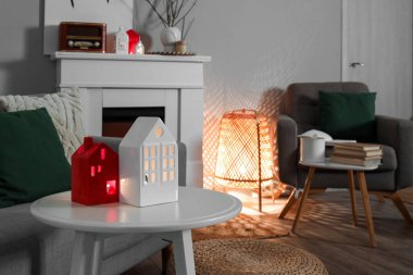 Glowing house candle holders on table in living room, closeup