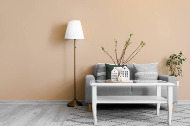 Interior of living room with sofa, table and house candle holders
