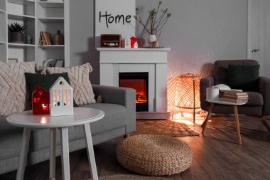 Interior of living room with fireplace, glowing lamp and house candle holders