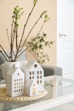 House candle holders and vase with tree branches on table in living room, closeup