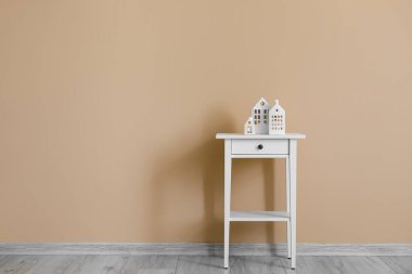 Glowing house candle holders on table near beige wall