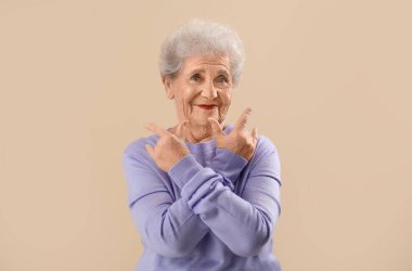 Senior woman in lilac sweater showing 