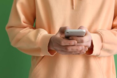 Man using mobile phone on green background, closeup