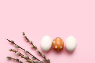 Composition with beautiful Easter eggs and willow branches on pink background