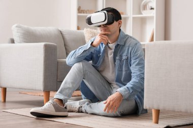 Young man using VR glasses at home