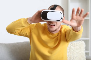 Young man using VR glasses at home