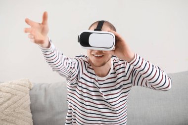 Young man using VR glasses at home