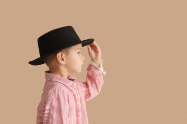 Cute little stylist in hat on beige background