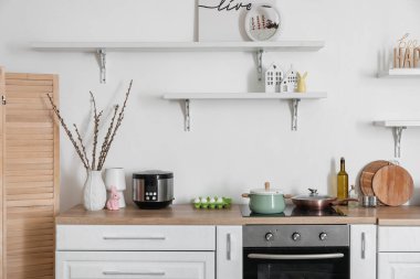 Vase with willow branches and Easter rabbit on counter in interior of kitchen