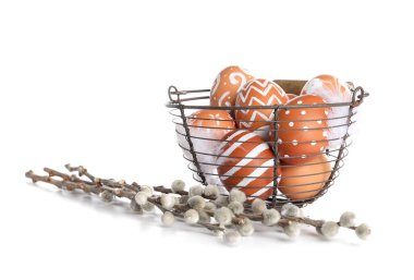 Basket with painted Easter eggs and willow branches on white background