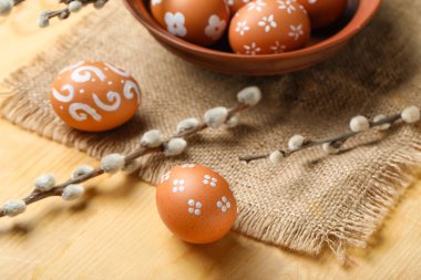 Painted Easter eggs and willow branches on wooden table, closeup