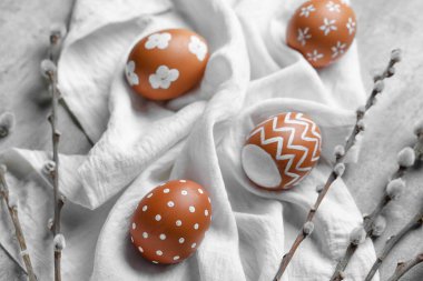 Composition with painted Easter eggs, willow branches and napkin on grunge background, closeup