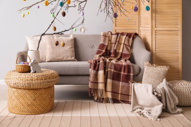 Interior of living room decorated for Easter celebration with sofa and tree branches