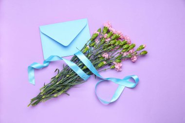 Bouquet of beautiful carnation flowers tied with ribbon and envelope on color background. Women's Day celebration