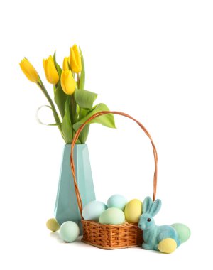 Basket with beautiful Easter eggs, toy bunny and tulip flowers on white background