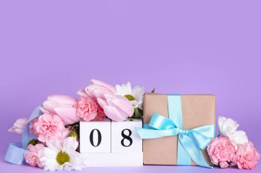 Cube calendar with date MARCH 8, gift box and beautiful flowers on lilac background. Women's Day celebration